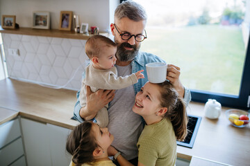 Sisters looking at newborn brother in fathers arms.