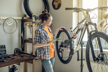 Woman fixing a mountain bike in a workshop. Concept of preparation for the new season, repair and maintenance