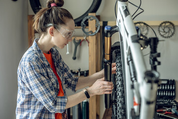 Woman fixing a mountain bike in a repair shop. Concept of preparation for the new season, repair and maintenance