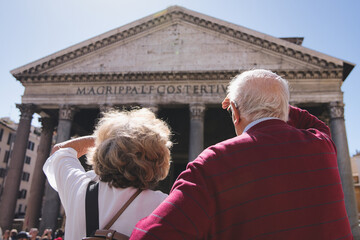Elderly couple shielding their eyes from the bright sun while admiring the pantheon in rome, a renowned historical landmark and popular travel destination rich in culture and history