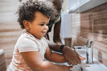 Child happily washing hands with an adult