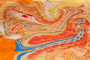 Illustrated orange, red and blue picture made by child painting on water in ebru style