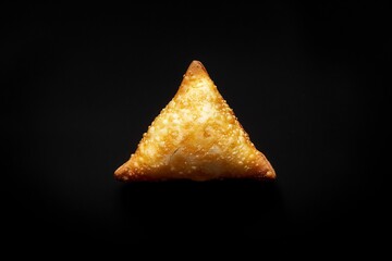 Minimalist macro shot of single golden brown fried samosa placed on a black background for dramatic contrast