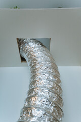 A shiny silver duct is creatively protruding from a small hole in the ceiling above, adding a...