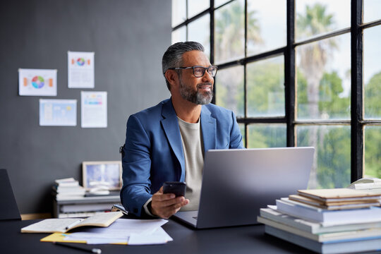 Pensive mature businessman thinking after a business call at work