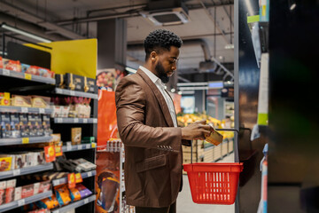 Side view of african american elegant man with shopping basket at supermarket purchasing groceries.