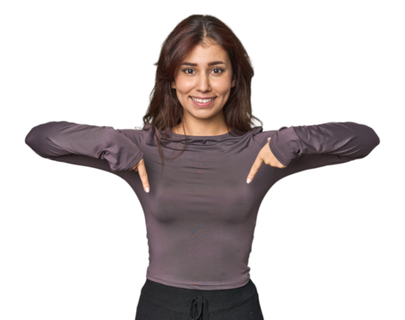 Middle Eastern woman in studio points down with fingers, positive feeling.