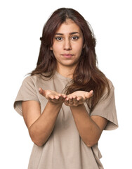 Naklejka premium Middle Eastern woman in studio holding something with palms, offering to camera.