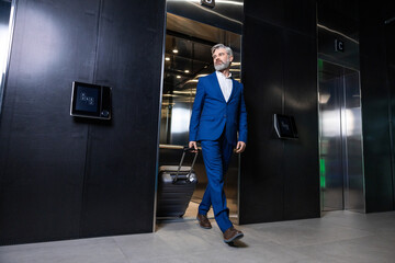 Elegant tall mature businessman goin g out of the elevator © zinkevych