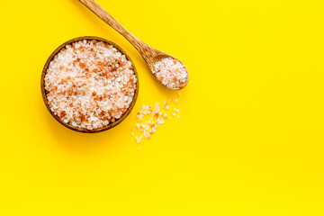 Coarse pink salt in wooden bowl and spoon and spilled salt. Cooking or spa concept