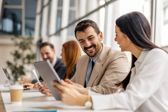 Data analysts sitting at boardroom with tablet and paperwork in hands and doing case study.