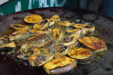 Hilsha fish is fried in a big pan along with shrimp and eggplant, Hilsha Fish and shrimp Simmering in mustard oil, traditional Bengali style fried hilsa and eggplant	