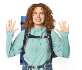 Young Caucasian redhead ready for hiking showing number ten with hands.