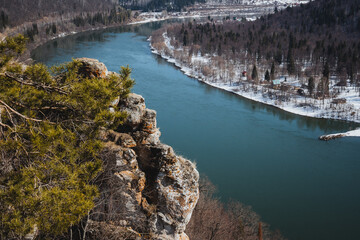 This captivating image shows an aerial view of a beautiful river flowing through a lush landscape filled with vibrant trees and rugged rocks, creating a breathtaking scene