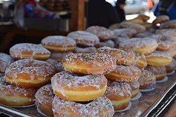 Sugar glazed doughnuts stacked a tray sprinkled with colorful toppings