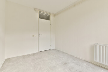 A bright minimalist interior featuring light walls and a simple design. The room includes a door and a radiator, showcasing a modern yet understated aesthetic.