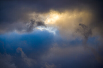 Sunlight breaking through multicolored dark storm clouds