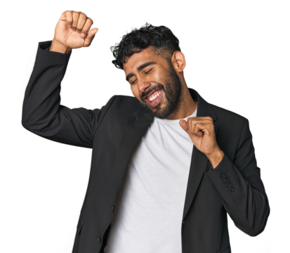 Hispanic businessman in suit in studio celebrating a special day, jumps and raise arms with energy.