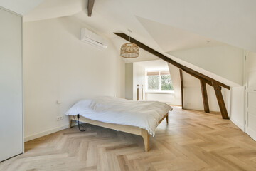 A spacious minimalist bedroom showcasing natural light, wooden flooring, and a cozy bed, reflecting a calm and serene atmosphere.