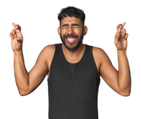 Young Hispanic man isolated crossing fingers for having luck