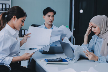 Fototapeta premium Young asian businesswoman suffering from headache while colleagues arguing and blaming her for bad work results during stressful office meeting