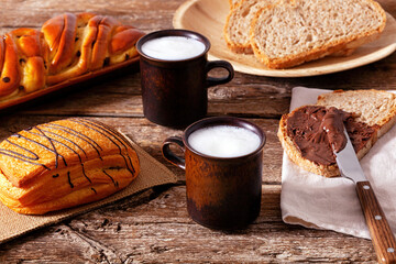 Delicious breakfast with whole wheat bread, chocolate cream, pastries and milk