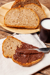 Spreading chocolate cream on a slice of whole wheat bread during breakfast