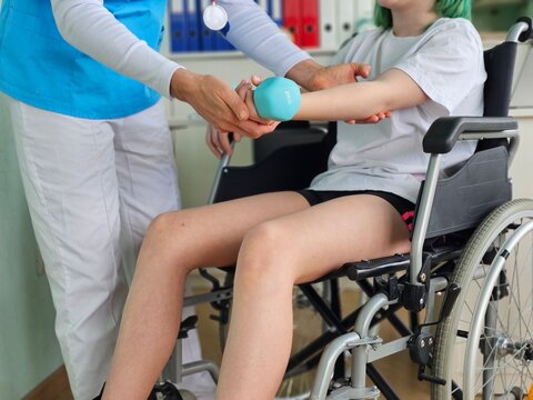 Interaction in a rehabilitation center with a patient, a child teenager in a wheelchair, receiving support