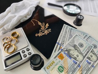 A collection of gold jewelry, including rings and chains, is displayed alongside stacks of cash on...