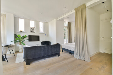 A stylish living room featuring a mix of modern furnishings, large windows that allow ample natural light, and a touch of greenery for a fresh ambiance.