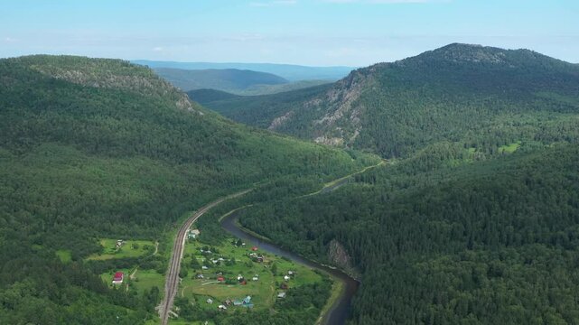 Breathtaking landscape showcasing the beauty of Ural mountains, a winding river, and a railway line near a picturesque village
