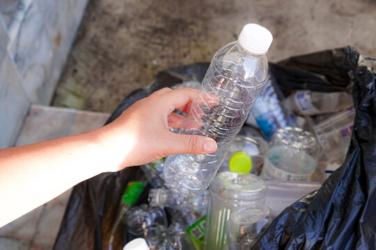 Image of used plastic water bottles being placed in black plastic garbage bags to properly separate waste according to the concept of sustainability at home.