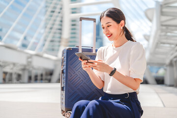 Business freelance adult asian woman using  smartphone with luggage for work and travel