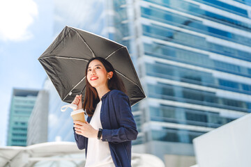 Business asian woman holding UV protection umbrella on sunny day city building background © dodotone