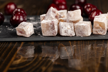 Turkish delight with cherry closeup, cubes of Turkish delight with the addition of red berries, reflection on the table