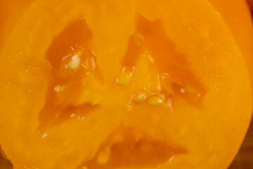sliced orange tomatoes on the board , whole clean washed tomatoes are sliced for cooking closeup