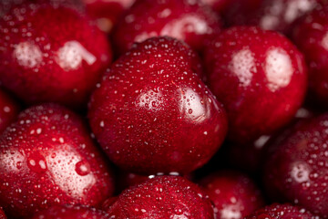 cherry berries in drops of water, wet red cherry fruits on the kitchen table closeup