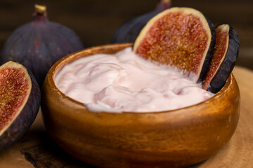 fresh yogurt with fresh figs, fresh pink yogurt with fig flavor in a wooden bowl with red figs, close up, side view