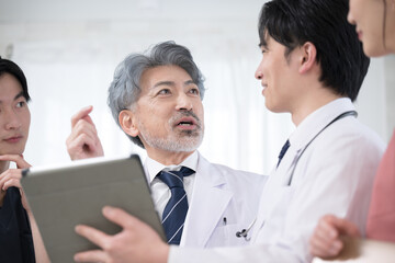 Obraz premium カルテや診察などの状況を確認するチーム医療の医師たち、 指導医と研修医のイメージ