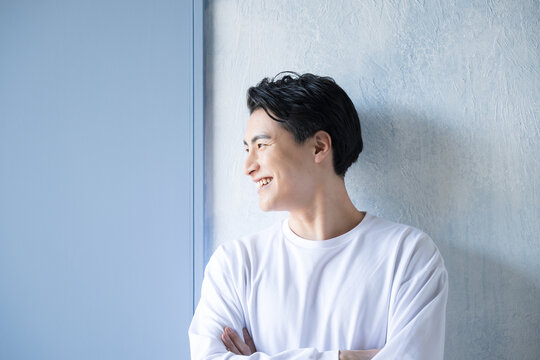 Tシャツを着た笑顔の爽やかな若い男性　扉が背景にある選択や未来のイメージの横顔
