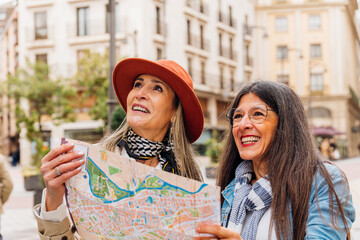 Happy senior women consulting a map in a city center