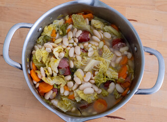Large pot of soup with beans, carrots, and cabbage. The soup is full and has a lot of ingredients