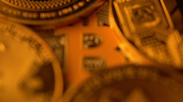 Macro closeup zoom in of stacked cryptocurrency coins with Bitcoin logo dominant
