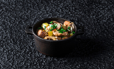 Hearty Meat and Vegetable Stew in a black pot on dark background.