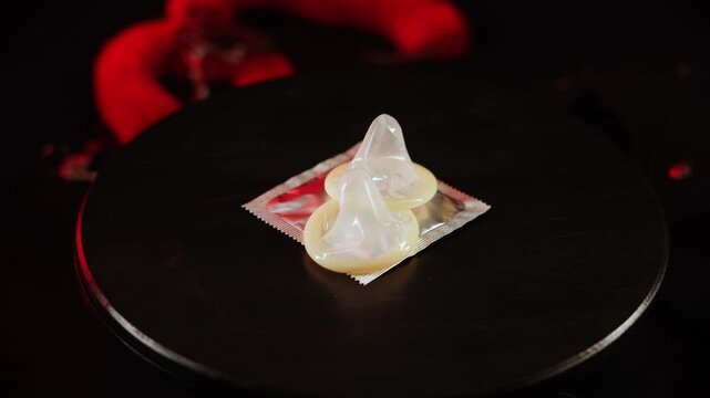 Condoms spinning on a black surface with dynamic lighting effects