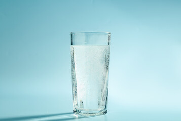 Soda water in glass on light blue background