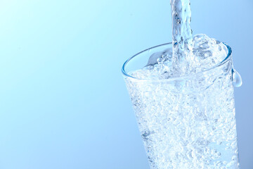 Pouring soda water into glass on light background, closeup. Space for text