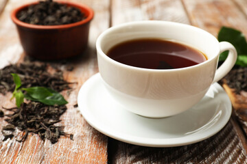Aromatic tea, brew and fresh leaves on wooden table, closeup