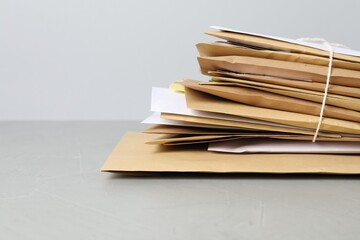 Post office. Stack of different paper envelopes on grey table, closeup. Space for text