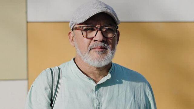 Serious hispanic senior man with beard and glasses